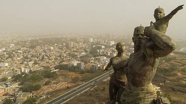 Brume de poussière saharienne au-dessus de la skyline de Dakar avec le Monument de la Renaissance africaine