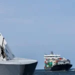 Navire porte-conteneurs et navires de guerre à l'entrée d'un port maritime