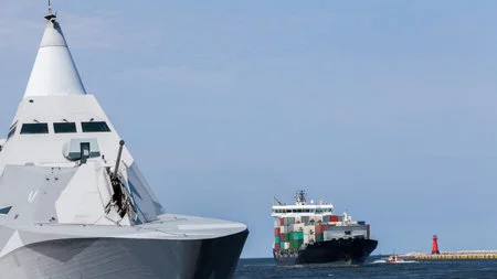 Navire porte-conteneurs et navires de guerre à l'entrée d'un port maritime