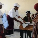 Bureau de vote dans une école avec des bulletins et une urne lors d'une élection en Afrique